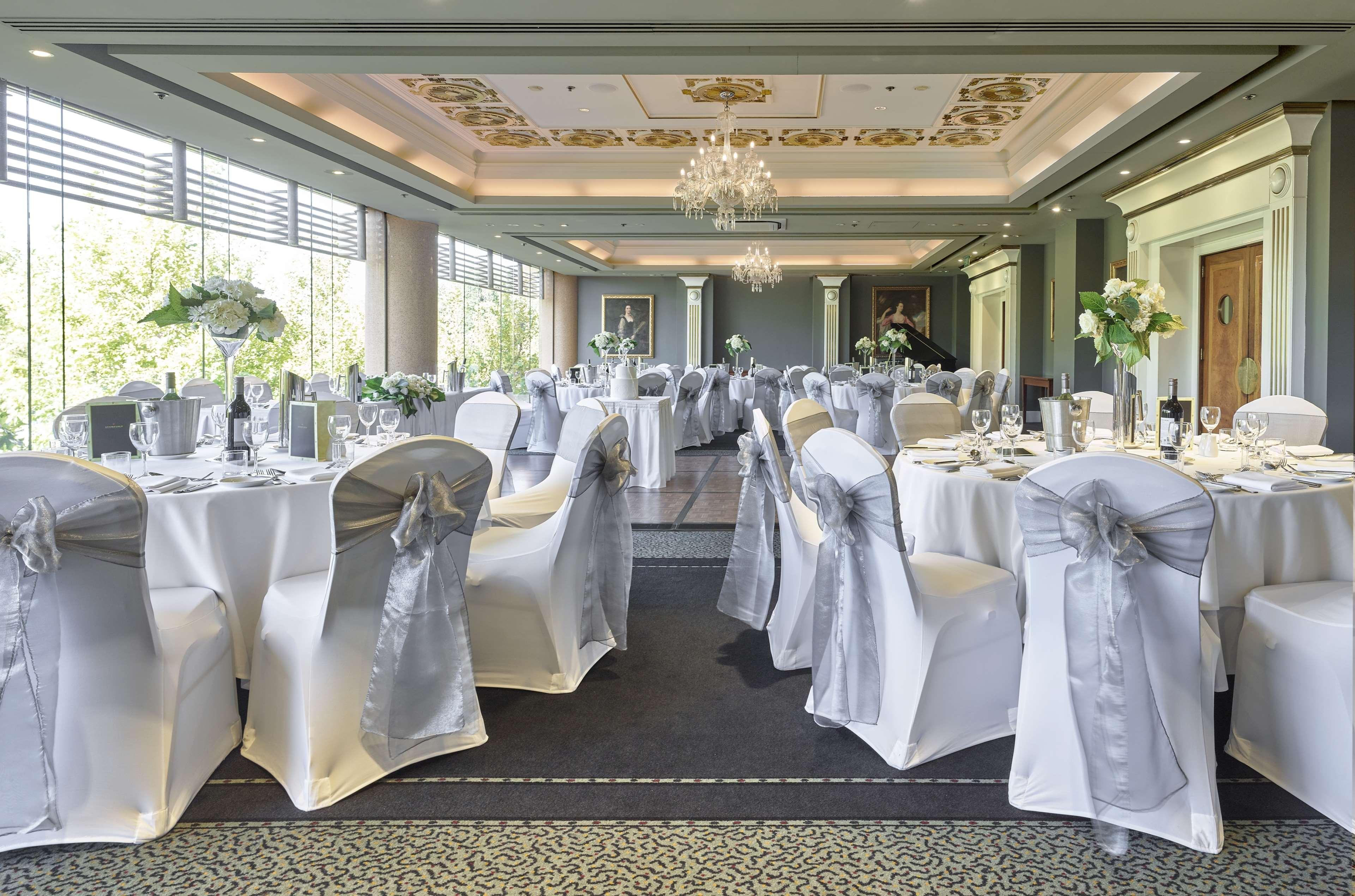 Hotel Stamford Plaza Adelaïde Extérieur photo The photo displays an elegantly arranged banquet hall. The room features several round tables covered with white tablecloths, each adorned with silver sashes on the chairs. There are floral centerpieces, possibly white flowers, on the tables, adding 